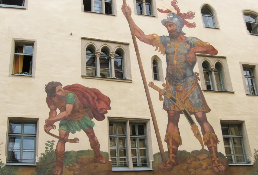 Wandbild am Goliathhaus in Regensburg: Der kleine David mit seiner Steinschleuder steht dem riesigen Goliath in Rüstung und mit Speer gegenüber.